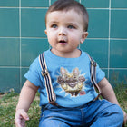 a toddler sitting in the grass wearing a blue t-shirt with the original OMG You're Home Fawn Frenchie dog design on the front in full color