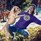 A woman playing with her dog wearing a purple hoodie featuring original Red Nose Pitbull rescue artwork by OMG You're HOME!